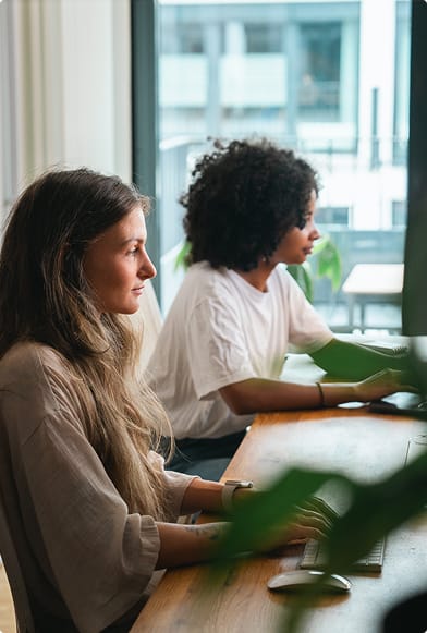 Zwei junge Frauen an einem Tisch beim fokussierten Arbeiten